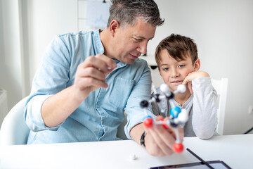 Father and son playing with atoms model, learning chemistry.