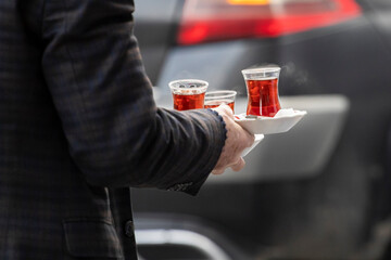 A man carries on street traditional Turkish tea served in the typical manner.