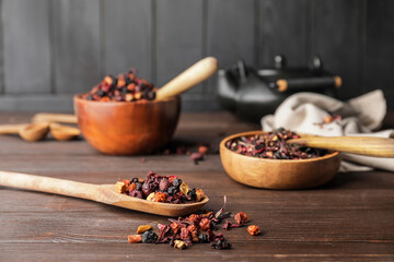 Spoon and bowl with dry fruit tea on wooden background