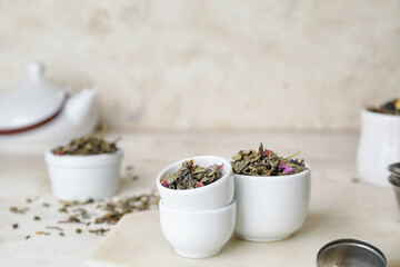 Bowls with dry fruit tea on light background