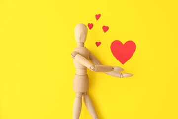 Wooden mannequin with hearts on color background