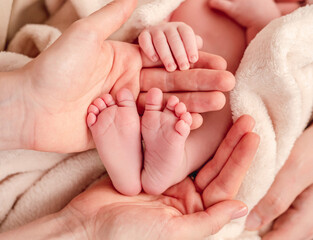 Obraz na płótnie Canvas Bare feet of newborn surrounded by family members hands