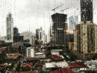 Water drops on glass of high rise looking onto a city that,s out of focus 