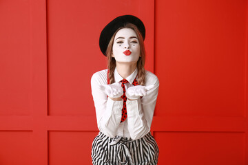 Female pantomimist blowing kiss on color background