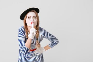 Female pantomimist showing silence gesture on grey background