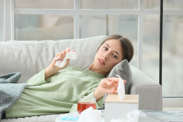 Sick young woman lying on sofa at home