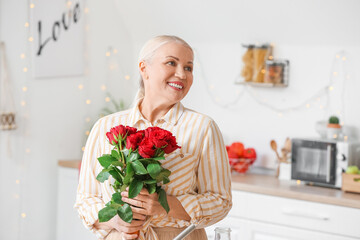 Mature woman with bouquet of beautiful roses at home