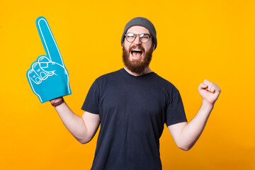 Photo of a a young man screaming of happiness with a fan glove on because his football team won .