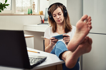 Woman listening online course in headphones, distance education. Freelancer sitting at workplace...