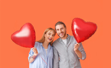 Young couple with air balloons on color background. Valentine's Day celebration