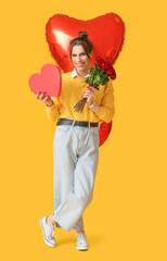 Young transgender woman with flowers and gift on color background. Valentine's Day celebration