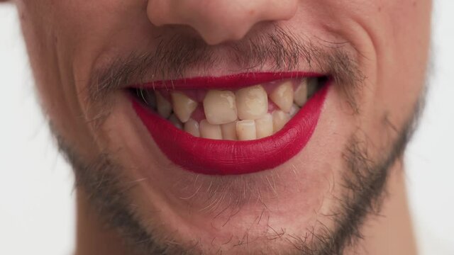 Close up view of mouth young ugly man with beard, moustache, red painted lips, stupid smiling, show broken teeth, look at camera isolated on white background. Guy with lonely grimace. Facial portrait