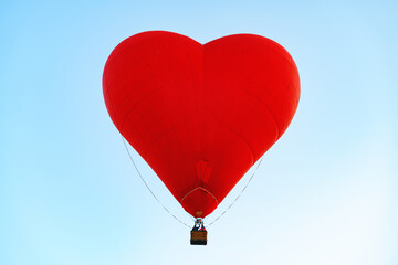 Fototapeta premium Red heart-shaped air balloon flying in the sky