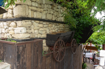Fototapeta premium Wall of an old house with a fake wagon in which ivy grows