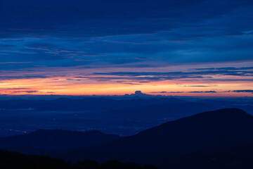 the twilight sky with orange and blue and city light from mountain view