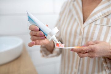 Close up picture of a woman squeezing toothpaste an a toothbrush