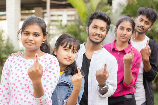 Group of teenager friends showing ink marked fingers outside polling station or booth after casting votes - Concept of Indian election or vote casting system.