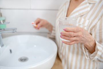 Obraz na płótnie Canvas Close up of elderly woman doing morning procedures in the bathroom