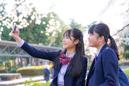 スマートフォンで自撮りをする女子学生2人