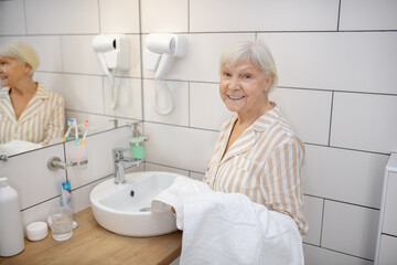 Fototapeta premium Gray-haired woman in the bathroom with a towel in hand