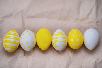Easter yellow decorated eggs on crumpled craft paper background. Minimal easter concept. Easter card with copy space for text. Top view, flatlay.