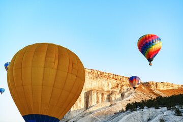 Colorful air balloons flying in clear sky near huge white mountain