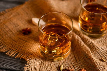 Scotch on wooden background with copyspace. Whiskey in shot glasses. Whiskey with cinammon and other spices.