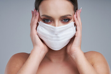 Portrait of beautiful woman in mask on gray background