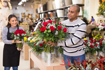 Friendly seller offering gift flower arrangement with roses to male buyer