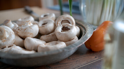 Champignon mushrooms on the table. Home kitchen. Sunny day. Close up. Soft focus in the background