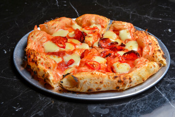 A Pepperoni pizza on black marble table background. Traditional Italian cuisine concept.