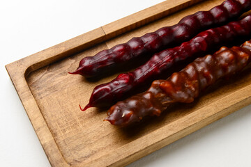 Churchkhela served on a wooden board over white background. Traditional Georgian dessert, Georgian cuisine concept.
