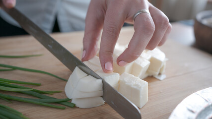 Slicing Georgian sulguni cheese on the table in the kitchen. Home cooking