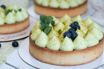 Round blueberry pie with green pistachio cream and strawberry jam by the window