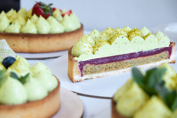 Three round shortbread pie with green pistachio cream and strawberry jam by the window. Pistachio pie with cream cheese