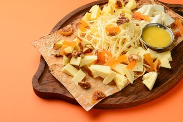 Cheese platter with different varieties of cheese served on lavash bread over orange background.