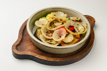 Baked vegetables: mushrooms, zucchini, eggplant served in ceramic bowl over white background.