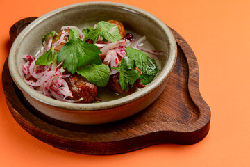 BBQ fiery sausages with vegetables served in a ceramic bowl over orange background. Delicious idea for dinner.
