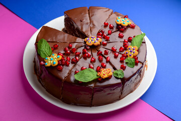 Christmas cake decorated with mint leaves and pomegranate seeds. Dark chocolate cake with choco topping.