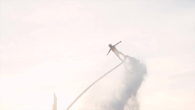 Unrecognizable flyboarders are making tricks with flyboards at sunset in slow motion 180p. High quality HD footage