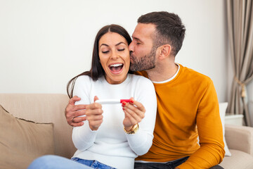 Happy young couple taking a pregnancy test at home. We become parents. young couple feeling happy after taking a pregnancy test at home