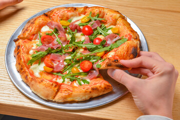 Young man eating a slice of pizza margherita. Still life, eating out concept. At restaurant or at home, pizza delivery.