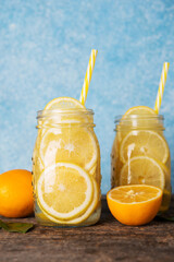 Homemade detox water with lemon in a glass jar on a rustic background