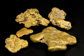 Real gold nuggets with black background taken in photography studio. Authentic natural jewelry. 