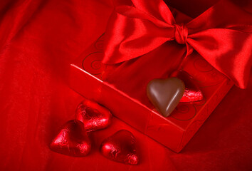 Valentine's Day. Gift box and candy in the form of a heart on a red background