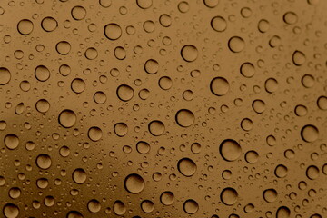 Close-up of water droplets and drops on a gold surface. Texture and structure after rain. Ecology. Vertical photography. Drops of different sizes.