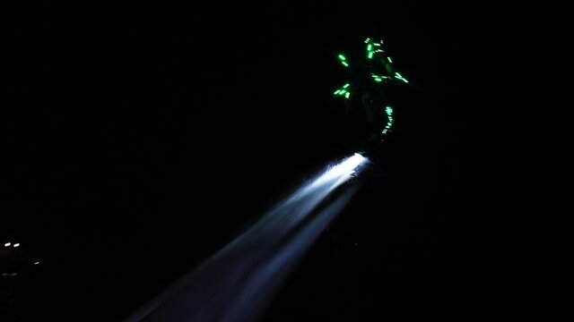 An unrecognizable flyboarder is making tricks at night in slow motion. High quality 4k footage