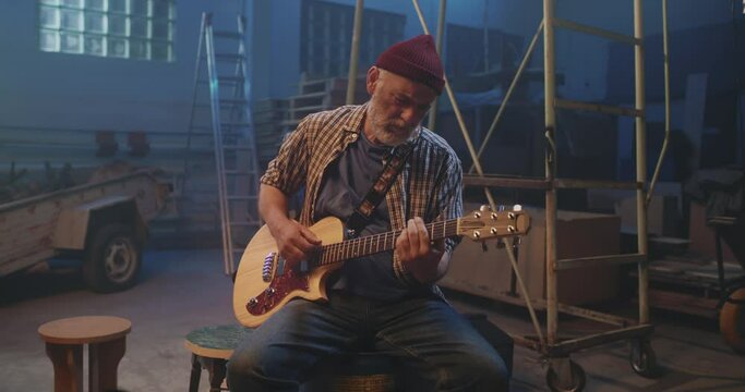 Mature guitarist playing song in garage