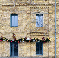 Fototapeta na wymiar Brick wall of building with windows and festive christmas decoration, garlands.