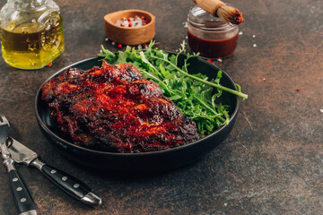 Homemade barbecued ribs seasoned with a spicy basting sauce and served with fresh arugula on a...